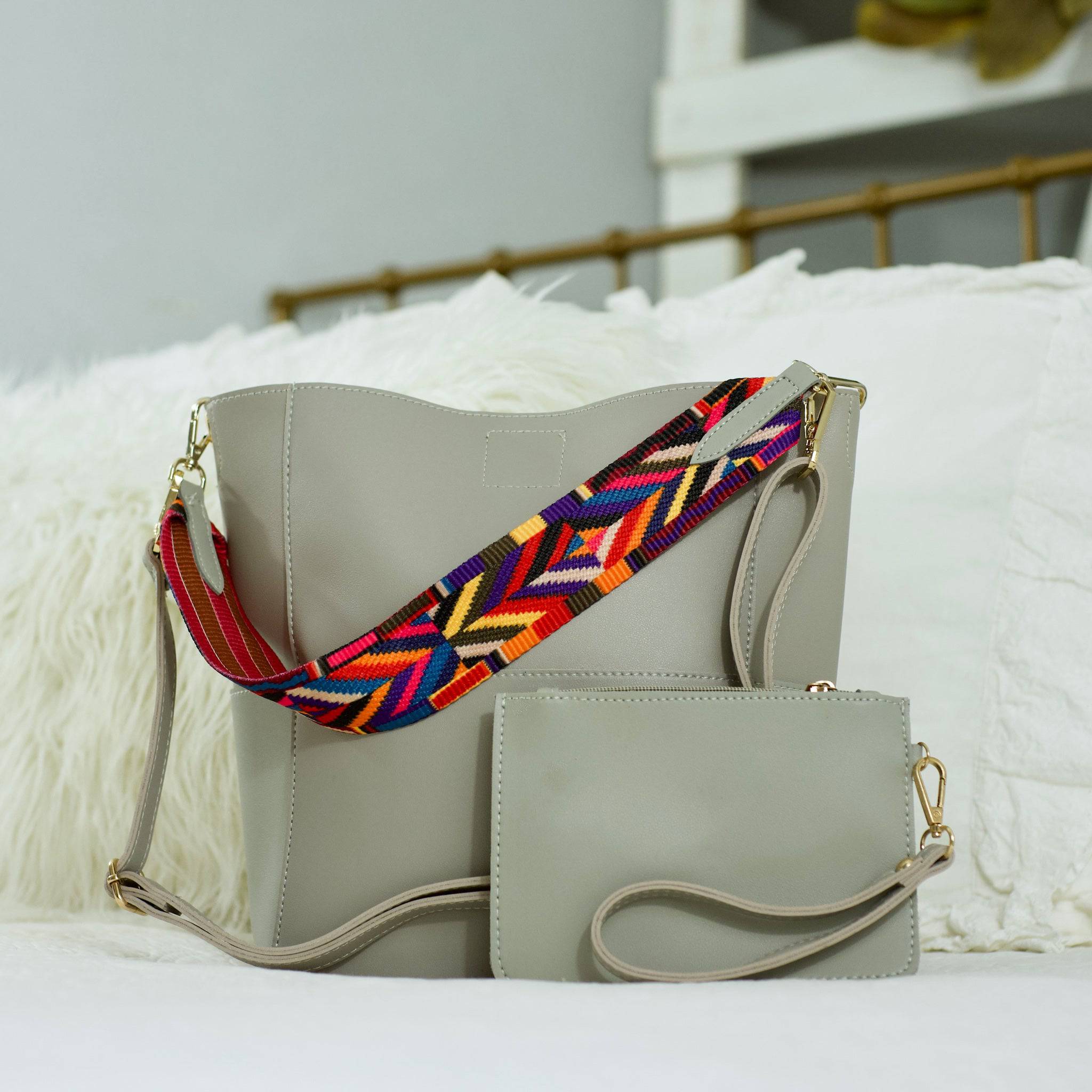 A woman sits on a bench, placing a Threaded Pear wristlet into her large Jordyn Handbag.