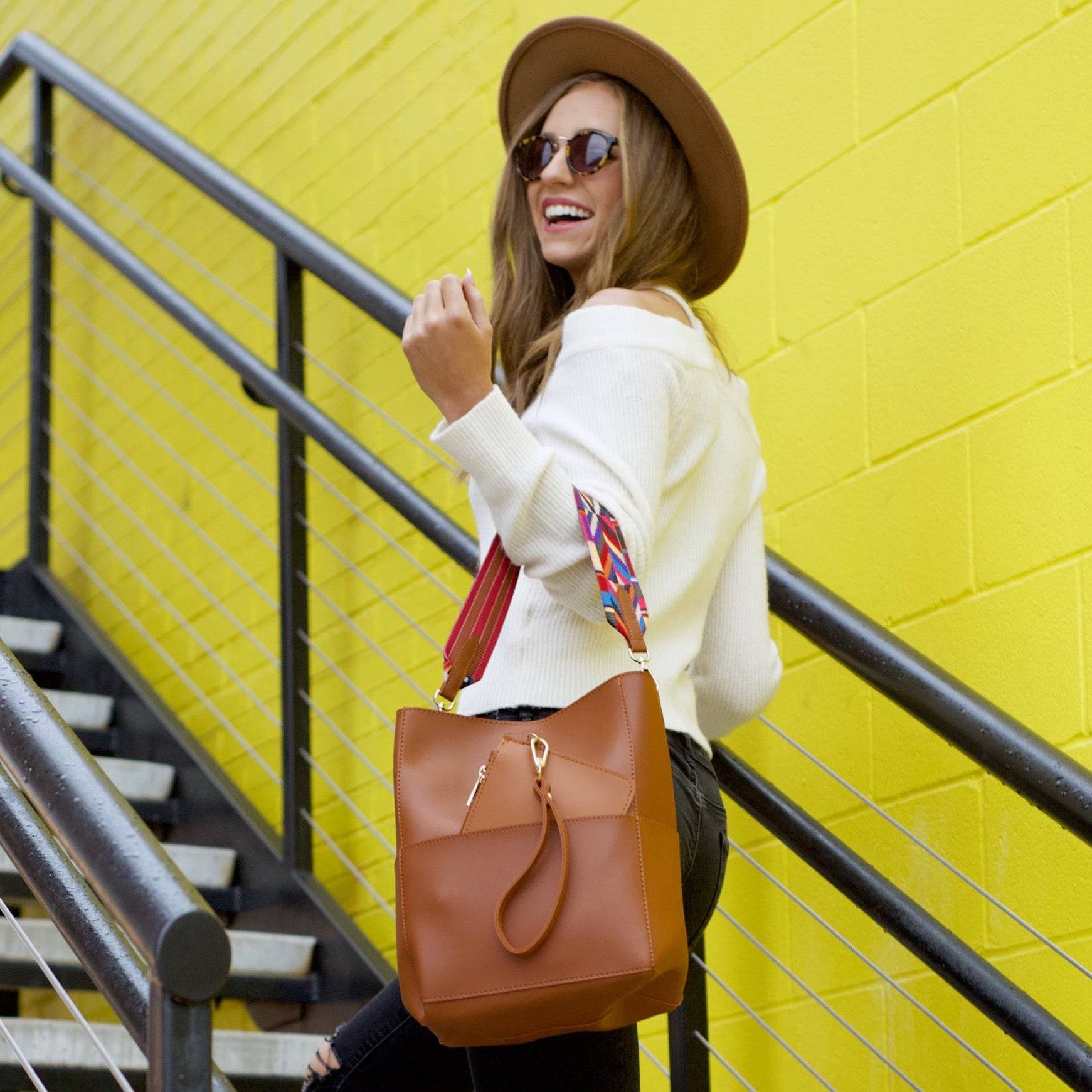 A woman sits on a bench, slipping a wristlet into her larger Jordyn Handbag with its spacious interior.