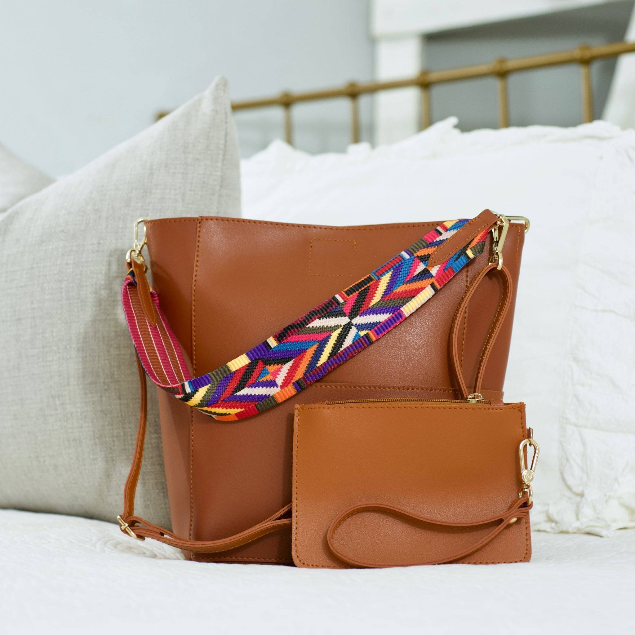 A woman sits on a bench, placing a Threaded Pear wristlet into her large Jordyn Handbag.