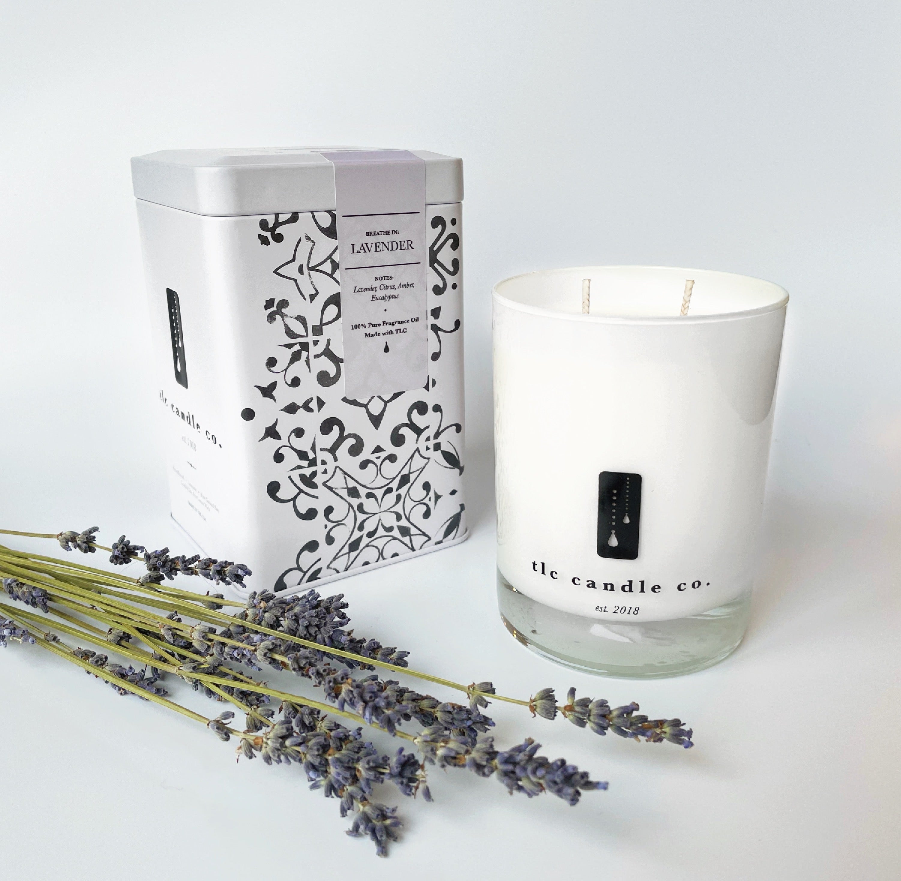 An 11 oz Lavender Soy Candle sits beside a decorative box labeled "Lavender" and a bundle of dried lavender sprigs, infused with calming essential oils.