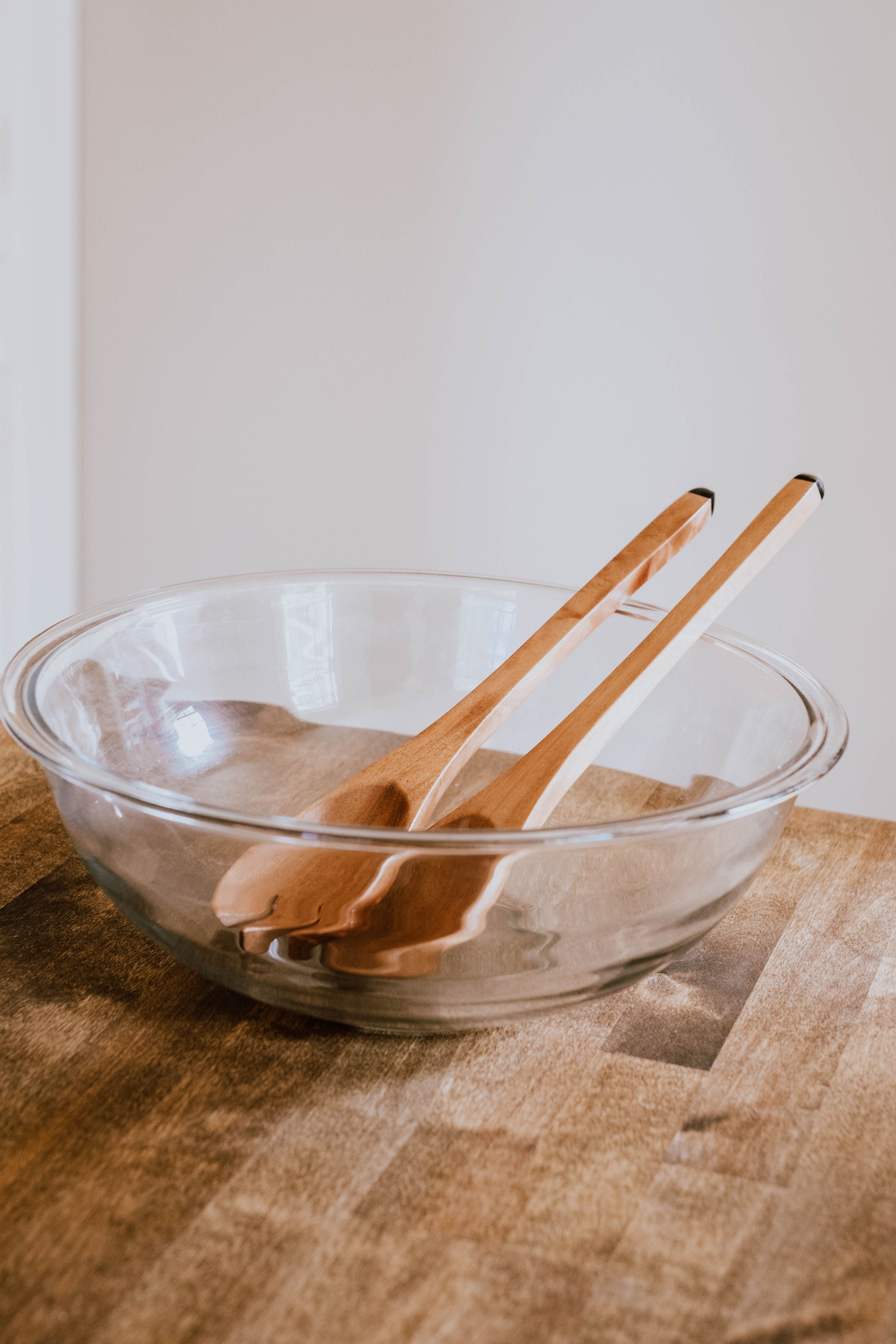 The Suzy Salad Servers, with horn-tipped handles, are elegantly displayed against a white background, complemented by sprigs of eucalyptus.