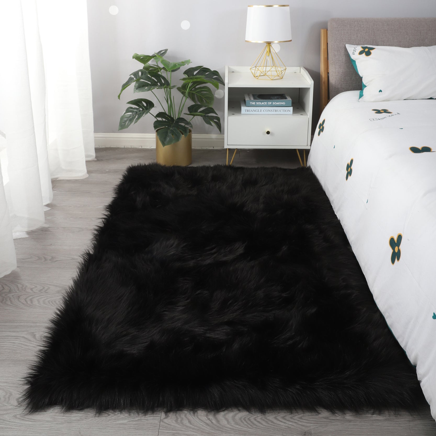 A modern living room featuring a large, Cozy Ultra Soft Fluffy Faux Fur Black Area Rug with an open book on it, a tan sofa, and a side table with a potted plant, against a backdrop of sheer