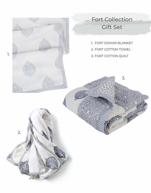 A Going Home Newborn Bed + Bath Gift Set by Ivory Meleager, consisting of white and black towels, blankets, and pillows.