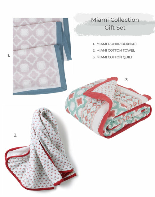 A Going Home Newborn Bed + Bath Gift Set by Ivory Meleager, consisting of white and black towels, blankets, and pillows.