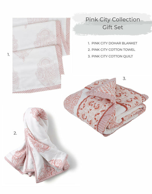 A Going Home Newborn Bed + Bath Gift Set by Ivory Meleager, consisting of white and black towels, blankets, and pillows.