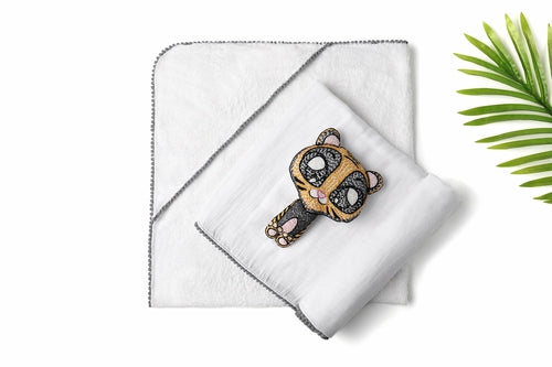 A white 3 Pc Newborn Essential Set - Hooded Towel, Swaddle + Toy Rattle by Ivory Meleager on top of a bed.