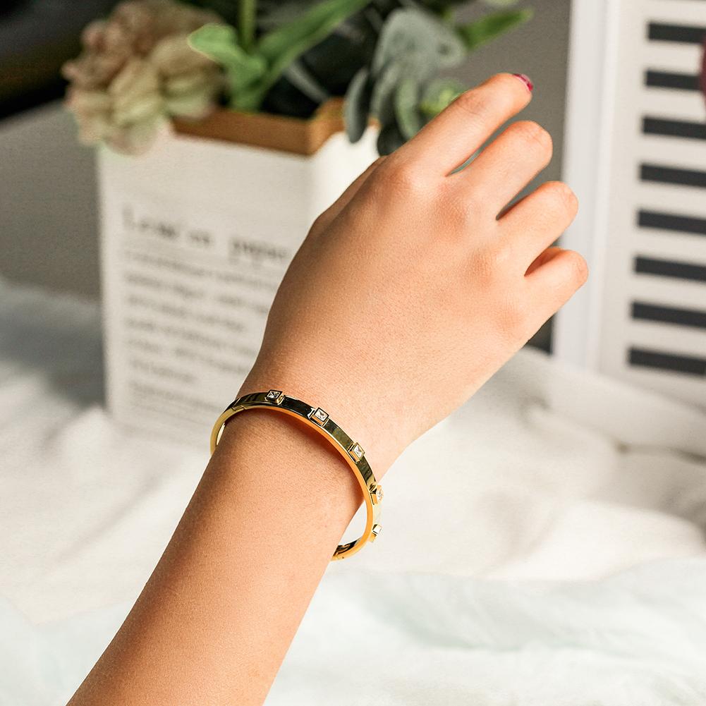 The Metal Stone Hinged Bangle is a sleek 14K gold PVD plated stainless steel bracelet, featuring square diamond accents evenly spaced along its hypoallergenic band.