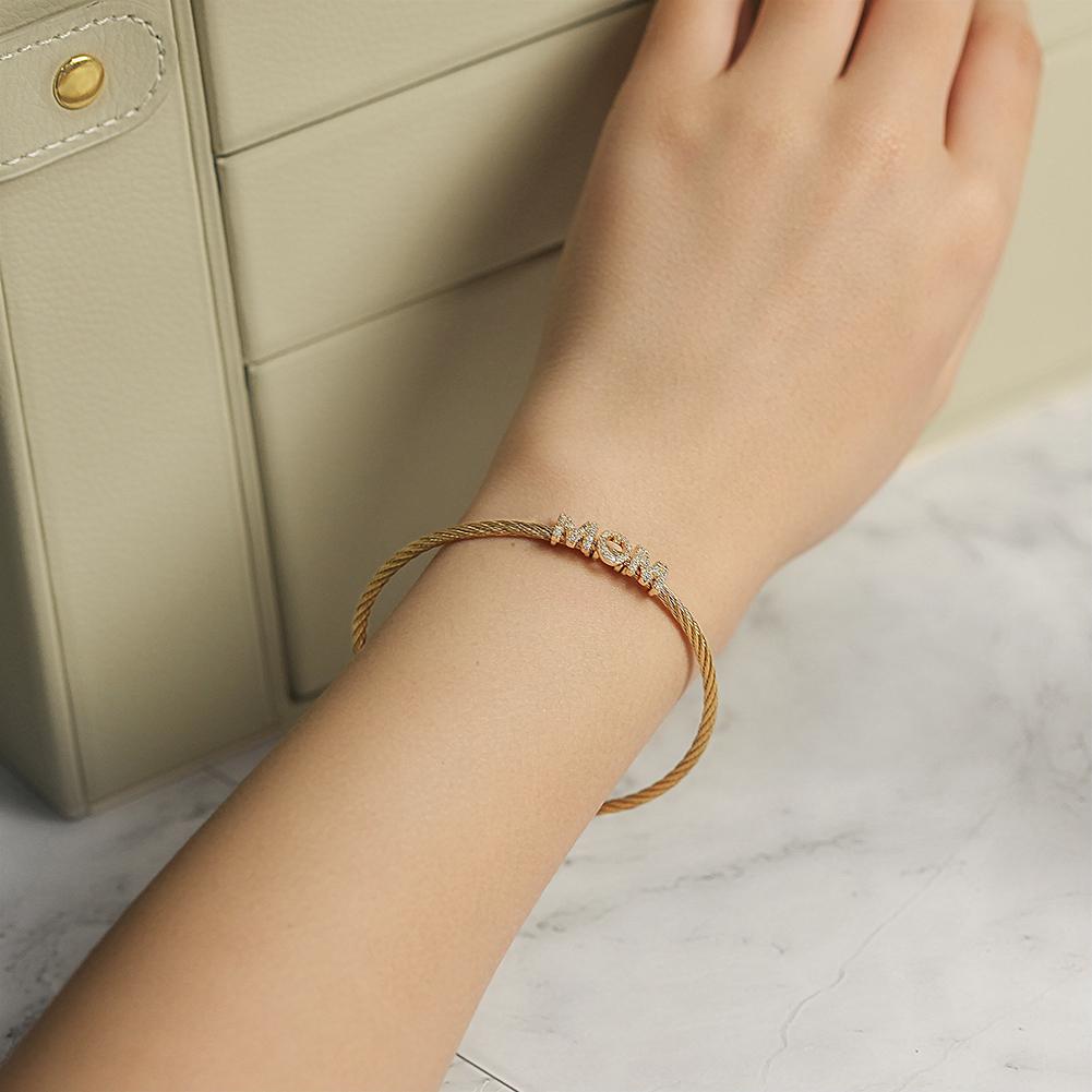 The "Mom" Pavé Bracelet displays "MOM" with diamond-studded letters on a cable chain, crafted from hypoallergenic 14K gold PVD plated material for enduring beauty and comfort.