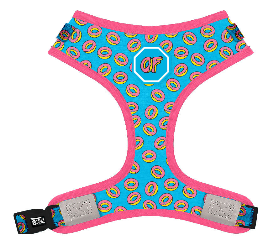 The Odd Future x Fresh Pawz Adjustable Mesh Harness includes a reflective tape design and a playful pattern of yellow and pink donuts on a blue background, complete with the iconic "OF" logo. This colorful pet accessory is part of the Fresh Pawz x Odd Future Donut collection and is highlighted by a stylish pink border.