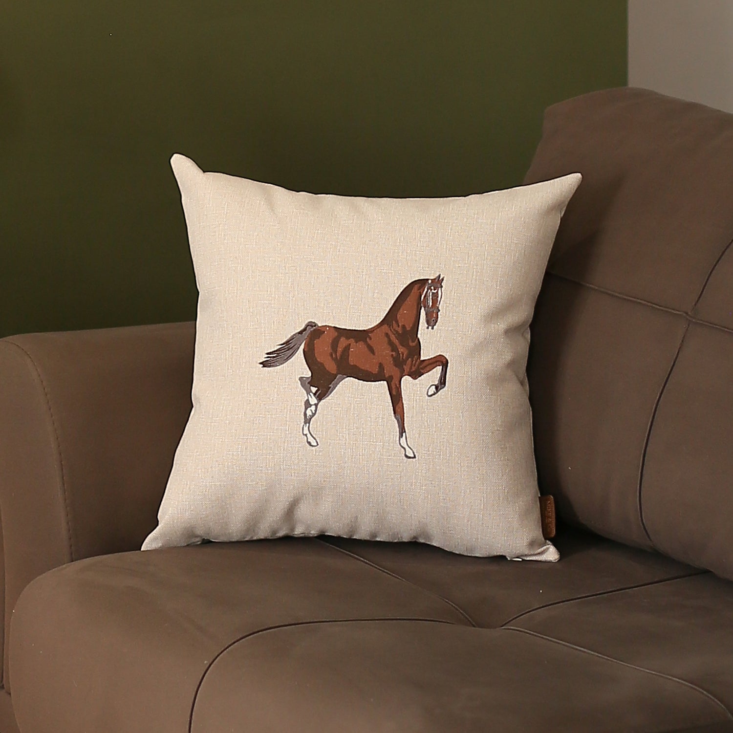 Placed on a brown sofa is the Boho Embroidered Horse Throw Pillow, a solid beige and brown square cushion measuring 18" x 18", featuring an illustration of a horse and made with recycled polyester filling, ensuring OEKO-TEX certification.