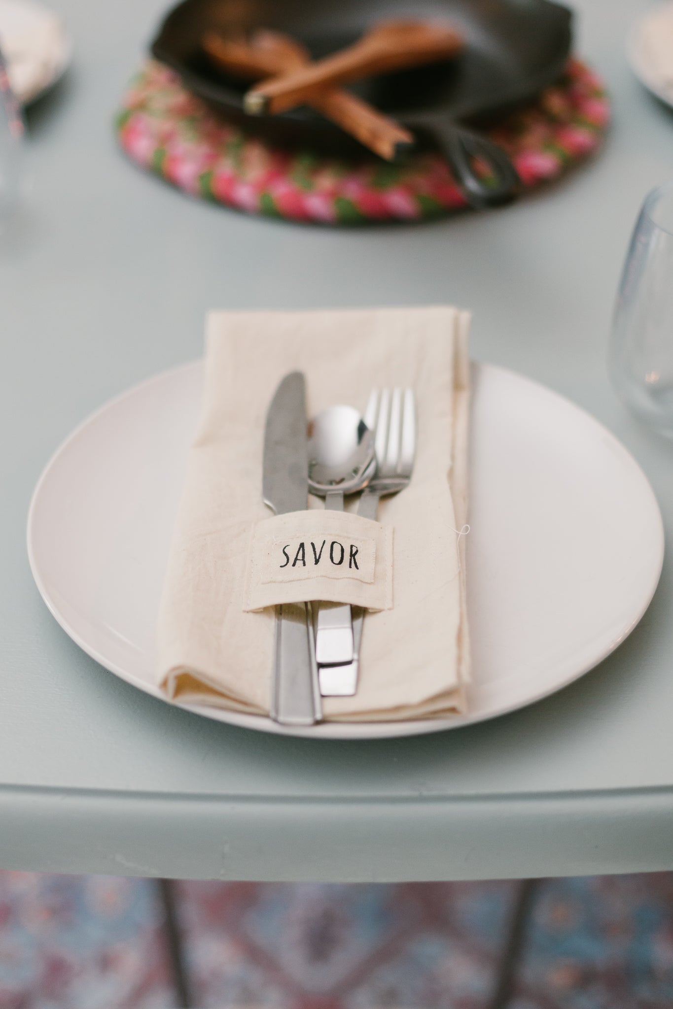 Pocket napkin set of four, skillfully crafted from up-cycled fabric, folded with a eucalyptus sprig and wooden ring, labeled "SAVOR.