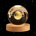 The 60cm 3D Crystal Ball Glass Ball Warm Night Light sits elegantly on a wooden base, showcasing a stunning solar system galaxy model. Nearby, an astronaut figurine adds to the scene's charm in a softly lit room. Experience quick delivery and safe transactions for this extraordinary astronomy-inspired home decoration.