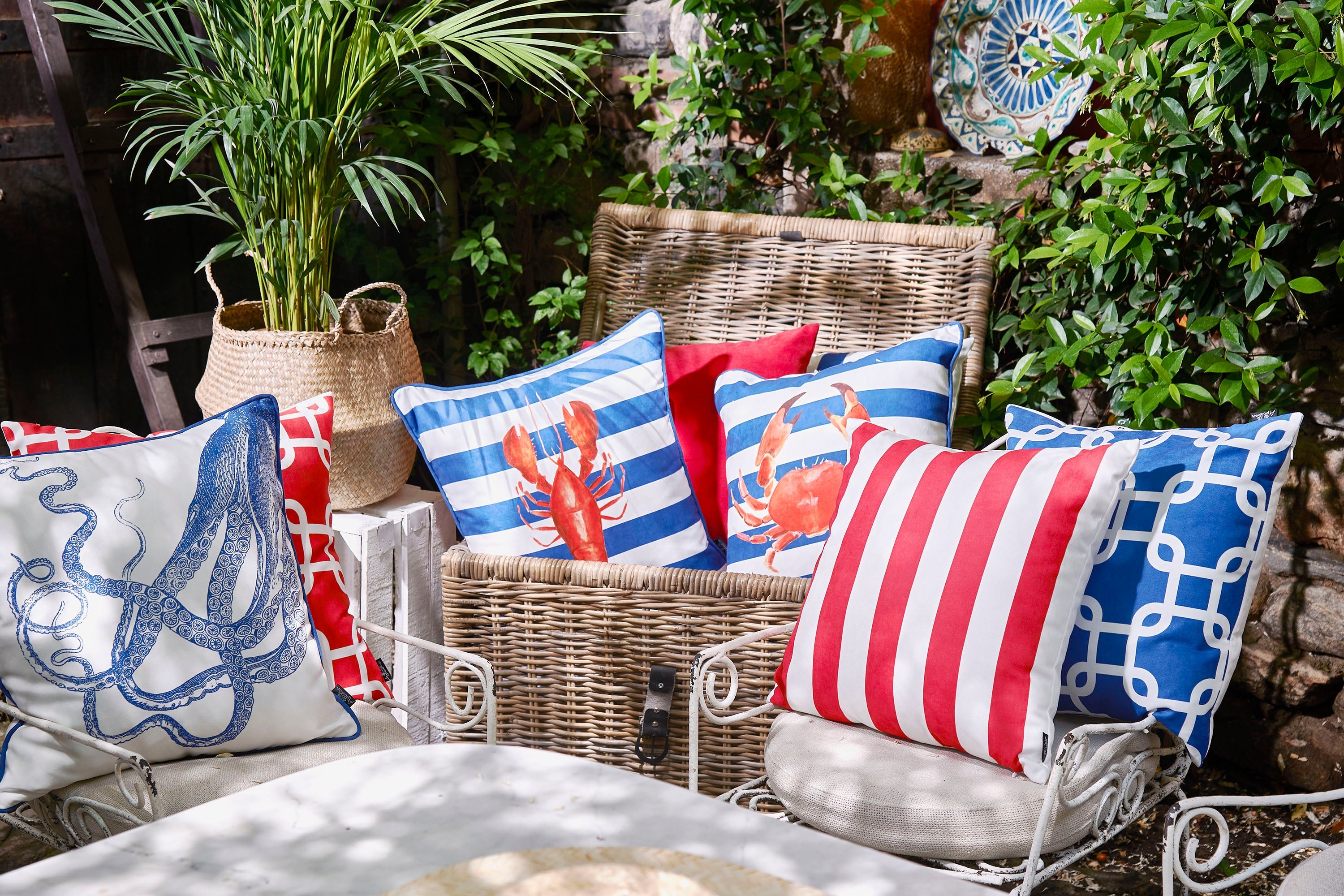 A set of two Nautica Octopus 18" square throw pillow covers, showcasing high-quality digital prints of blue octopus designs, rests on a yellow sofa. With their hidden zipper closures, these decorative covers perfectly complement the green indoor plant in the sunlit room.