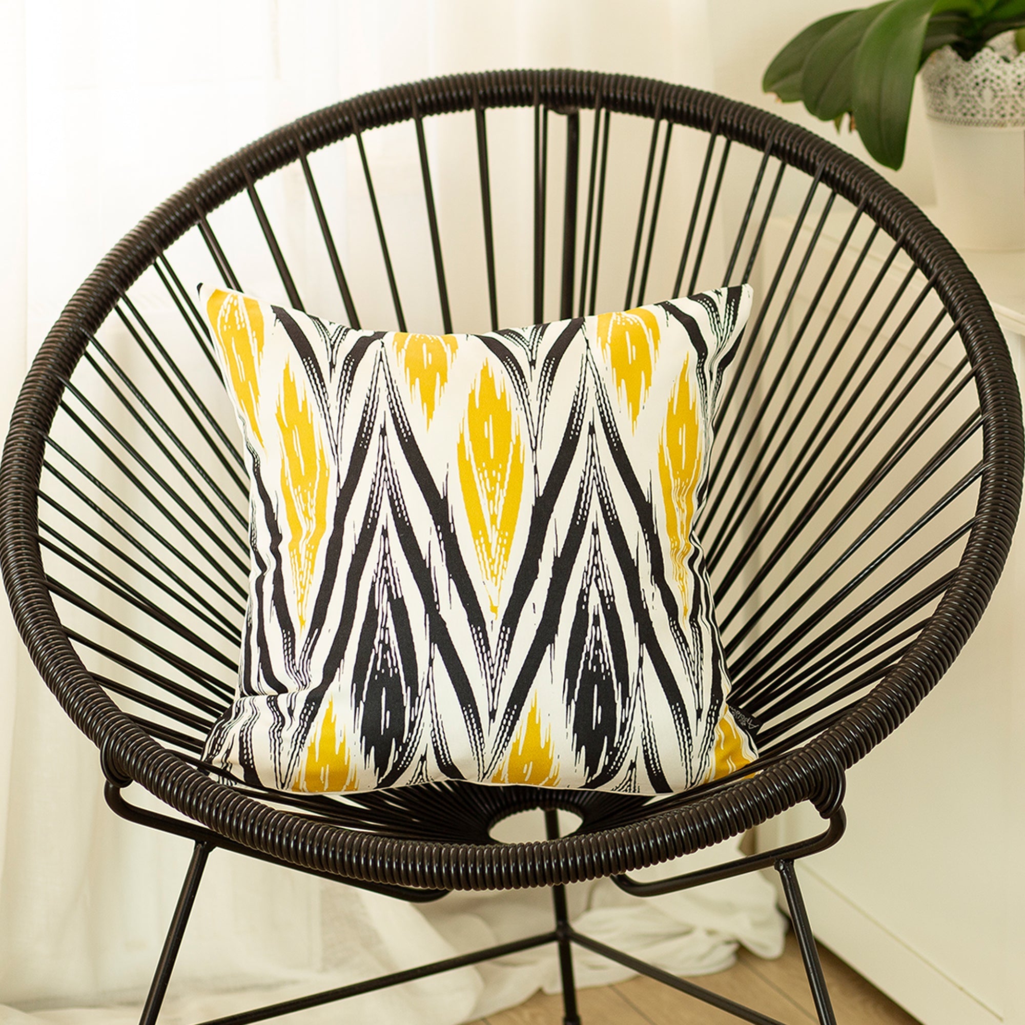 A gray sofa with Geometric Yellow Lit Square 18" Throw Pillow Covers sits in front of a tall lamp. A potted plant is near a stairway with floating steps, and a patterned rug graces the floor.