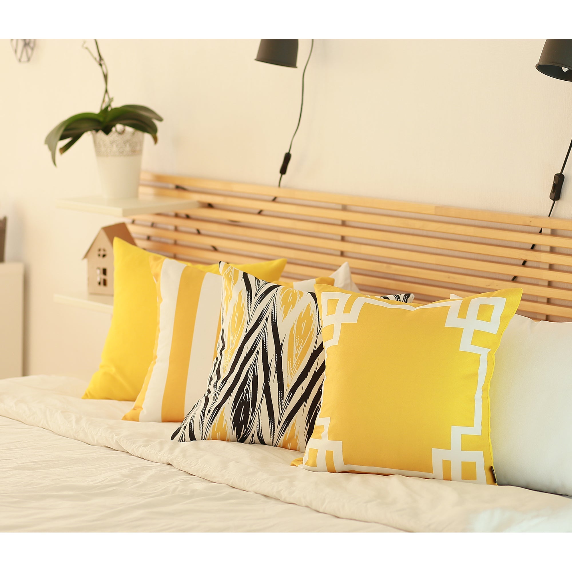 A gray sofa with Geometric Yellow Lit Square 18" Throw Pillow Covers sits in front of a tall lamp. A potted plant is near a stairway with floating steps, and a patterned rug graces the floor.