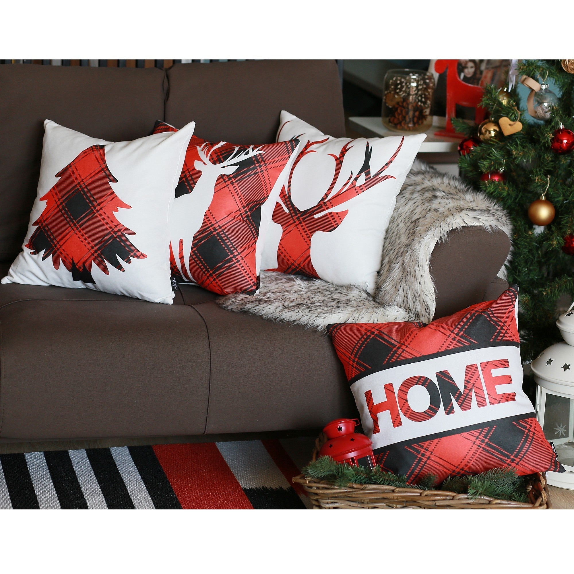 A sofa adorned with the Christmas Themed Decorative Throw Pillow Set of 4 in square 18" x 18" white and red designs, showcasing Christmas trees and reindeer, sits beside a beautifully decorated Christmas tree, complemented by a basket filled with more home décor pillows.