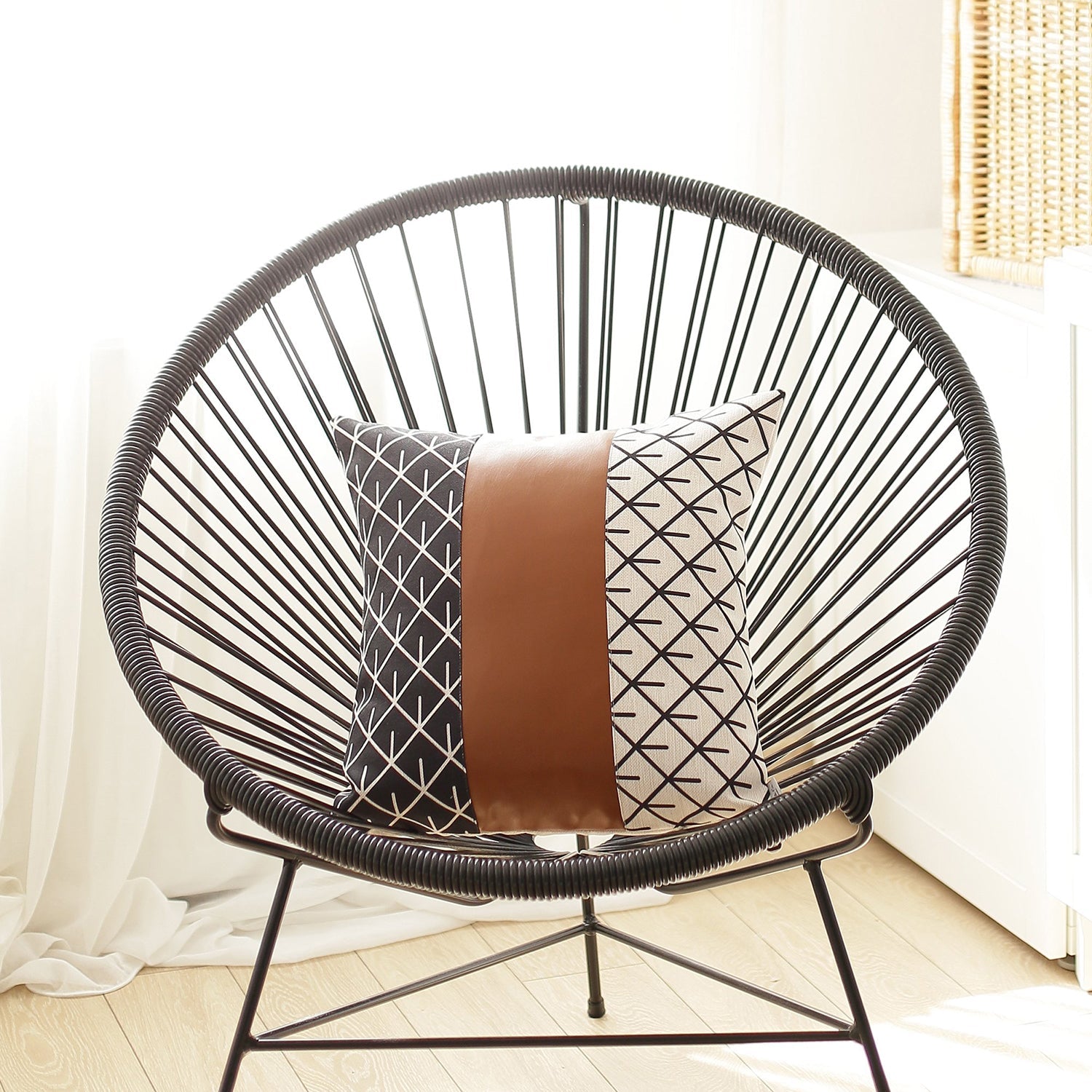 A brown couch decorated with a Bohemian Mixed Set of 2 Vegan Faux Leather Brown Geometric Throw Pillow Covers, enhanced by a knitted blanket and a plant in the background.