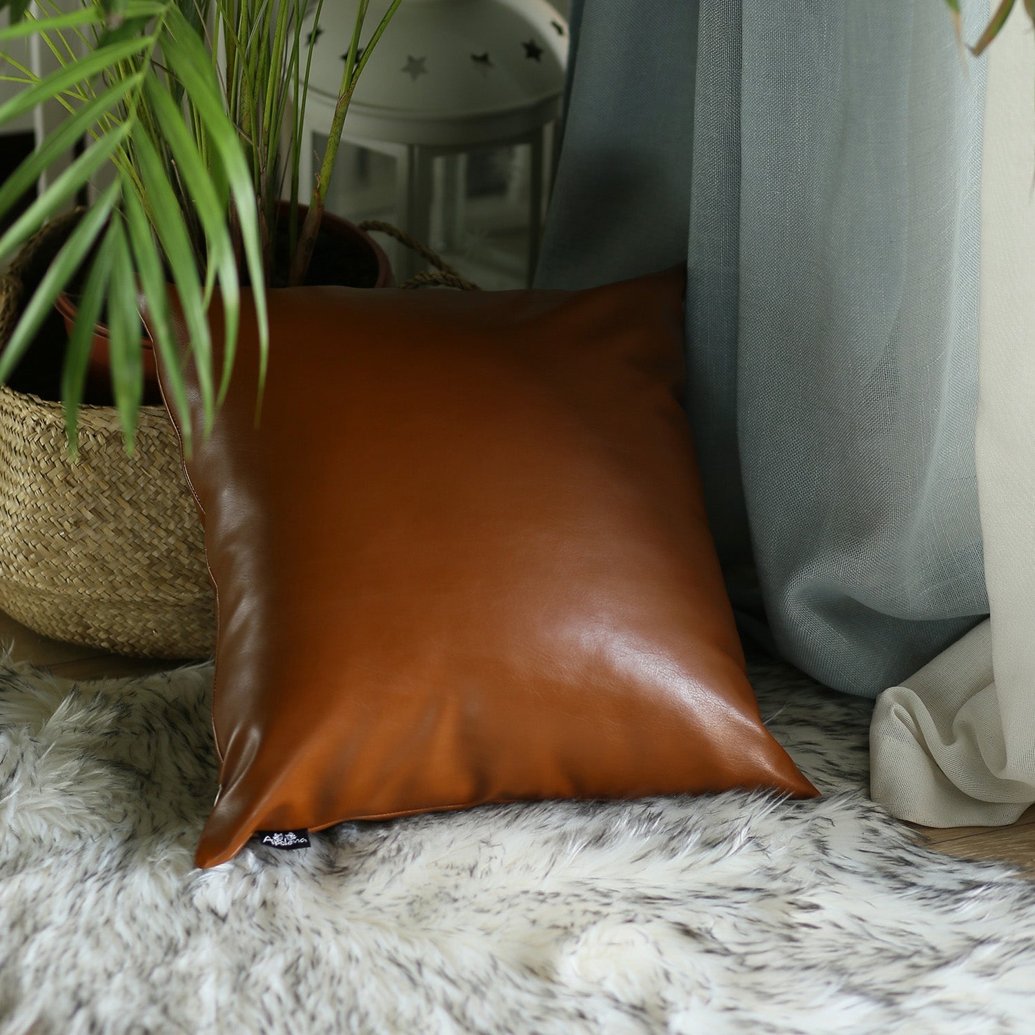 A brown couch decorated with a Bohemian Mixed Set of 2 Vegan Faux Leather Brown Geometric Throw Pillow Covers, enhanced by a knitted blanket and a plant in the background.