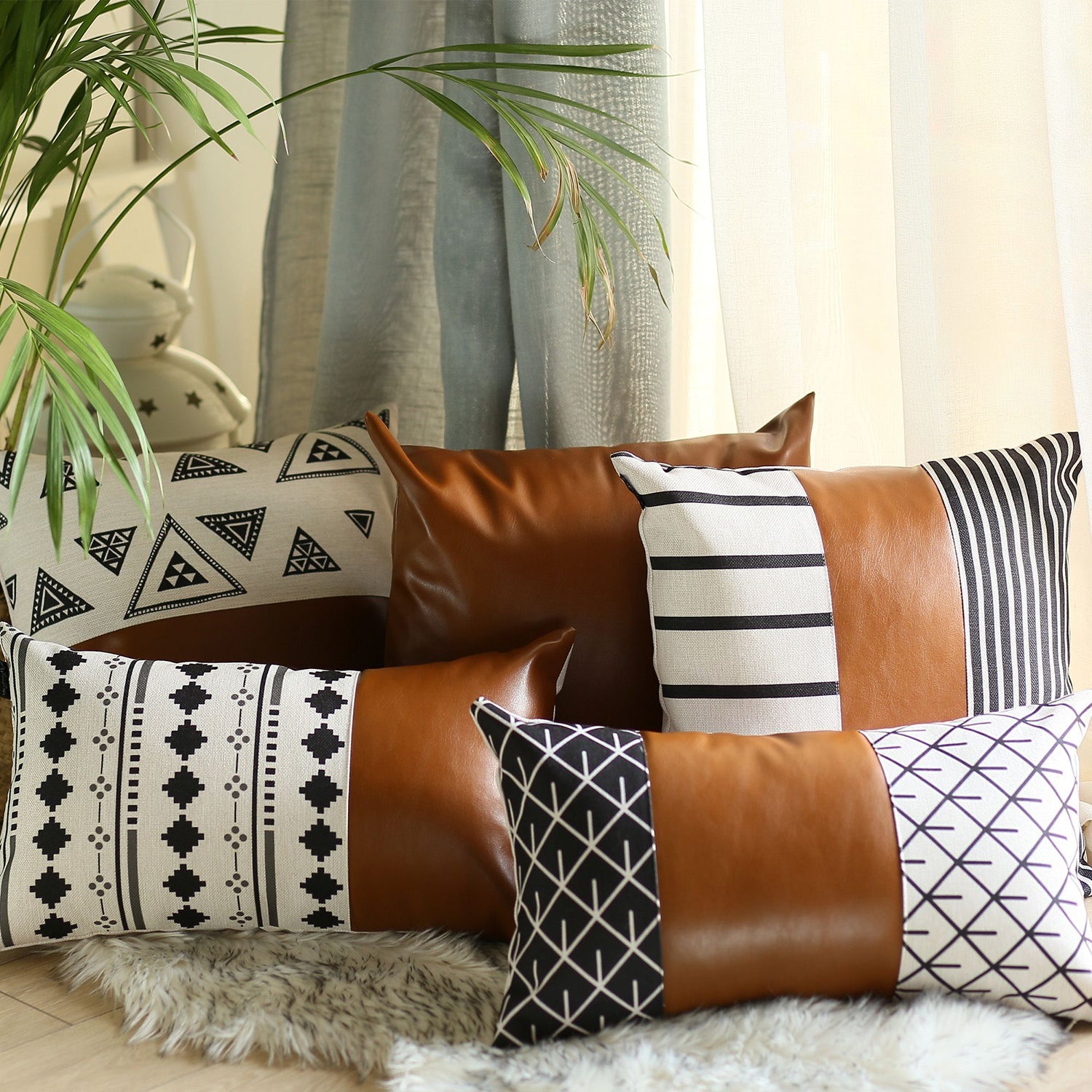 A brown couch decorated with a Bohemian Mixed Set of 2 Vegan Faux Leather Brown Geometric Throw Pillow Covers, enhanced by a knitted blanket and a plant in the background.