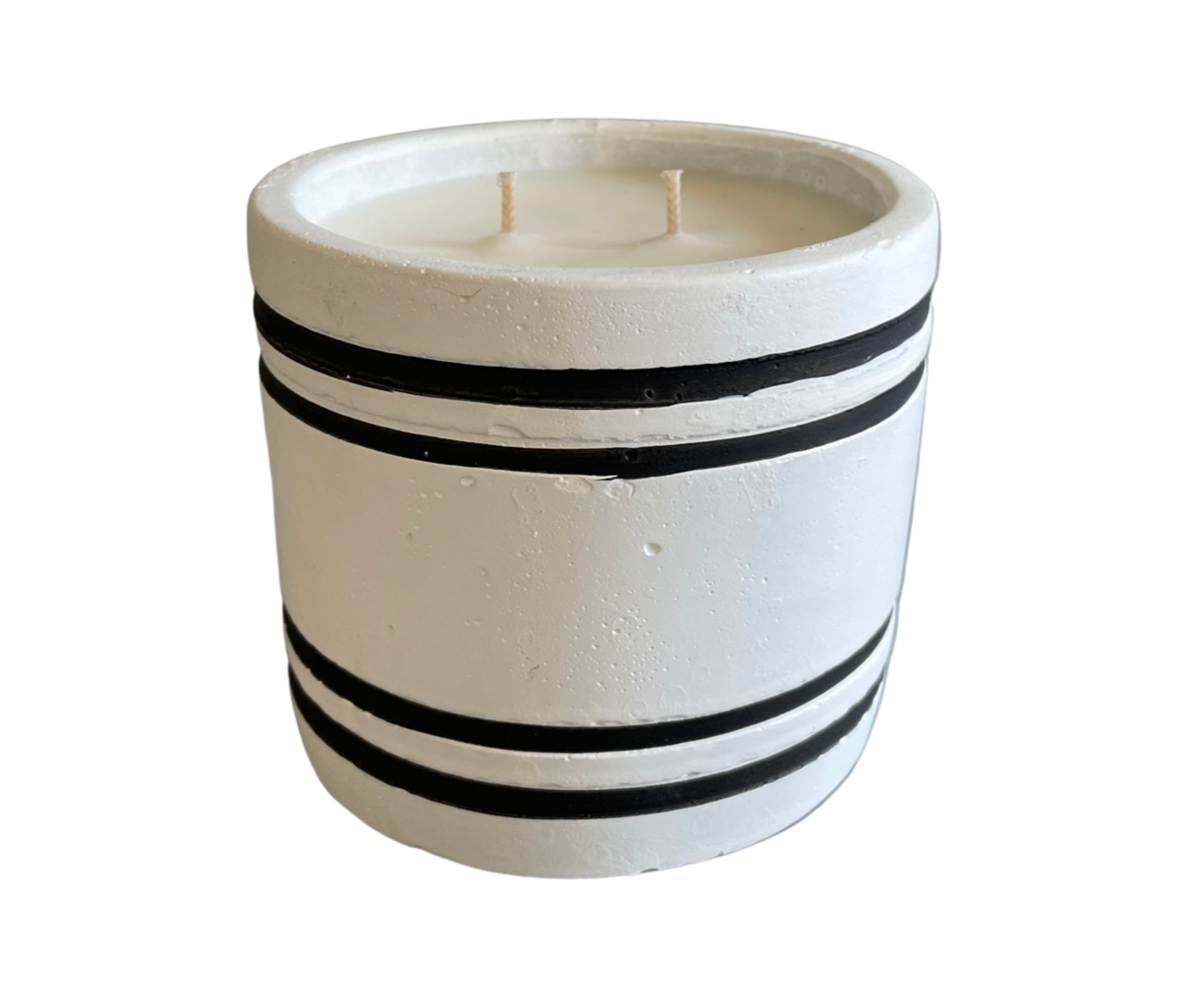 A luxury small striped stone designer candle labeled "Amber Noir" sits elegantly on a wooden stand, surrounded by artificial fruit and greenery. It adds a touch of sophistication to your home decor with its enticing notes of cedar, sandalwood, and amber.