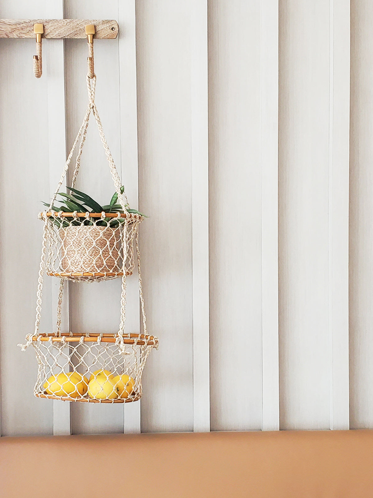 The Jhuri Double Hanging Basket is a macramé plant holder with two intricately woven baskets, each holding a lush green plant. Created by Fair Trade artisans, this piece showcases sustainably handmade craftsmanship and timeless elegance against a simple backdrop.