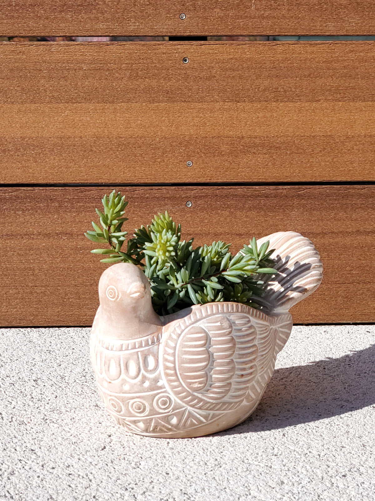 The Turtle Dove Terracotta Pot, intricately patterned and shaped like a graceful bird with a detailed tail, crafted meticulously by fair trade artisans, rests on a plain background.