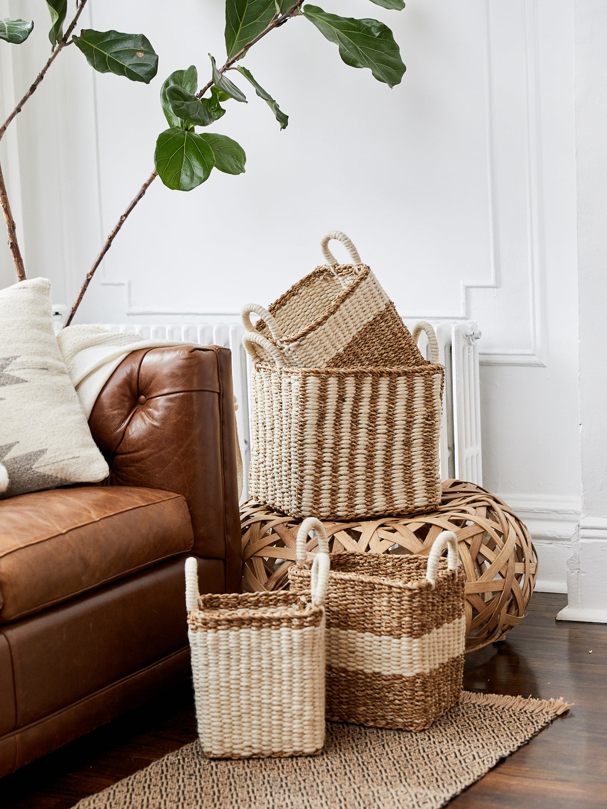 The Ula Storage Baskets, a set of three handmade options with handles in different sizes, are arranged in a row against a plain background. Made from jute wool, these Fair Trade baskets highlight artisanal craftsmanship and sustainable design.