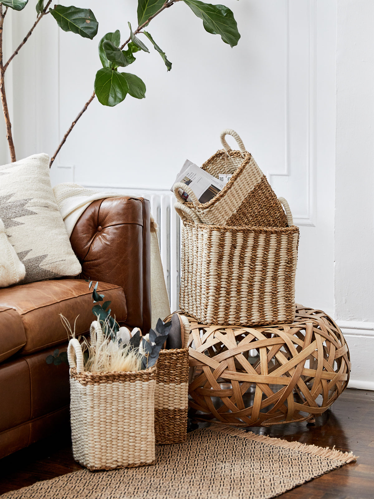 The Ula Storage Baskets, a set of three handmade options with handles in different sizes, are arranged in a row against a plain background. Made from jute wool, these Fair Trade baskets highlight artisanal craftsmanship and sustainable design.