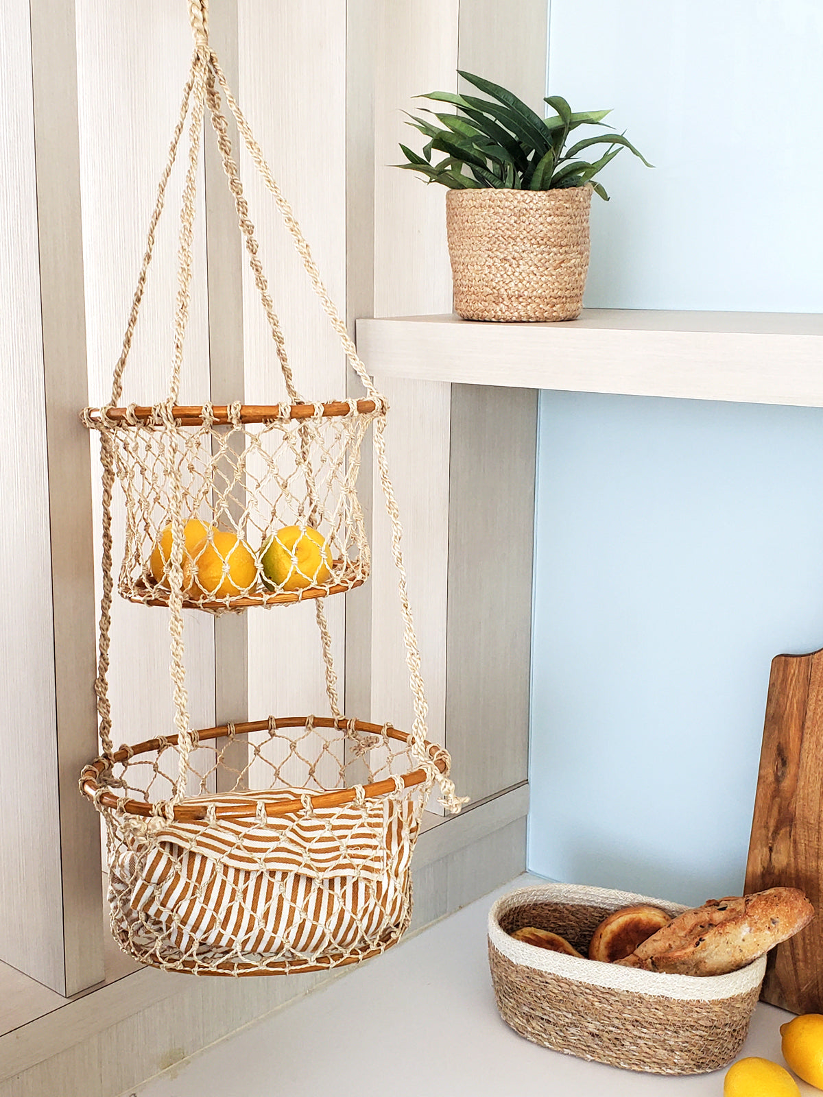 The Jhuri Double Hanging Basket is a macramé plant holder with two intricately woven baskets, each holding a lush green plant. Created by Fair Trade artisans, this piece showcases sustainably handmade craftsmanship and timeless elegance against a simple backdrop.