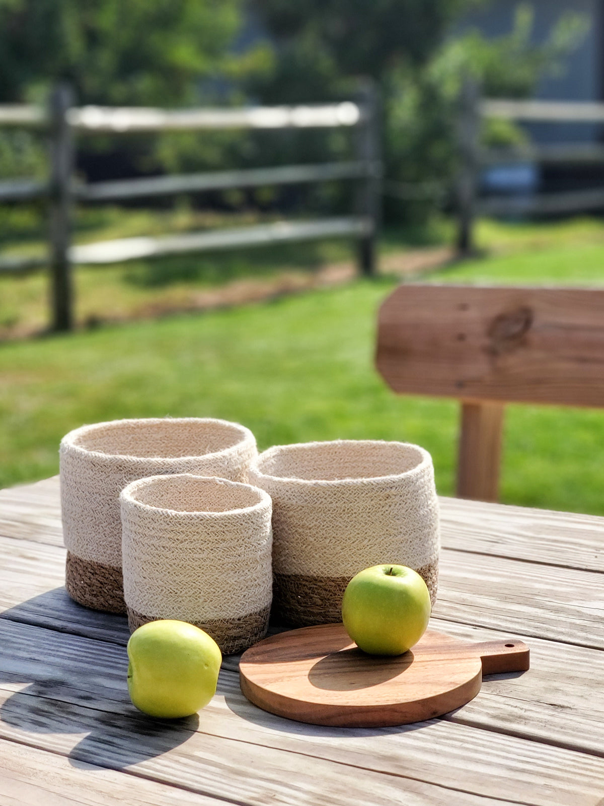 Three Savar Bins, woven sustainably by Fair Trade artisans in varying sizes, each featuring a beige upper half and a brown lower half, are arranged in a row.