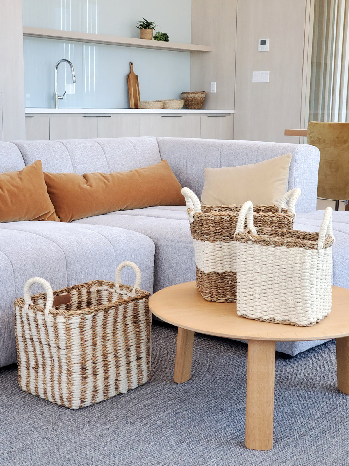 The Ula Storage Baskets, a set of three handmade options with handles in different sizes, are arranged in a row against a plain background. Made from jute wool, these Fair Trade baskets highlight artisanal craftsmanship and sustainable design.