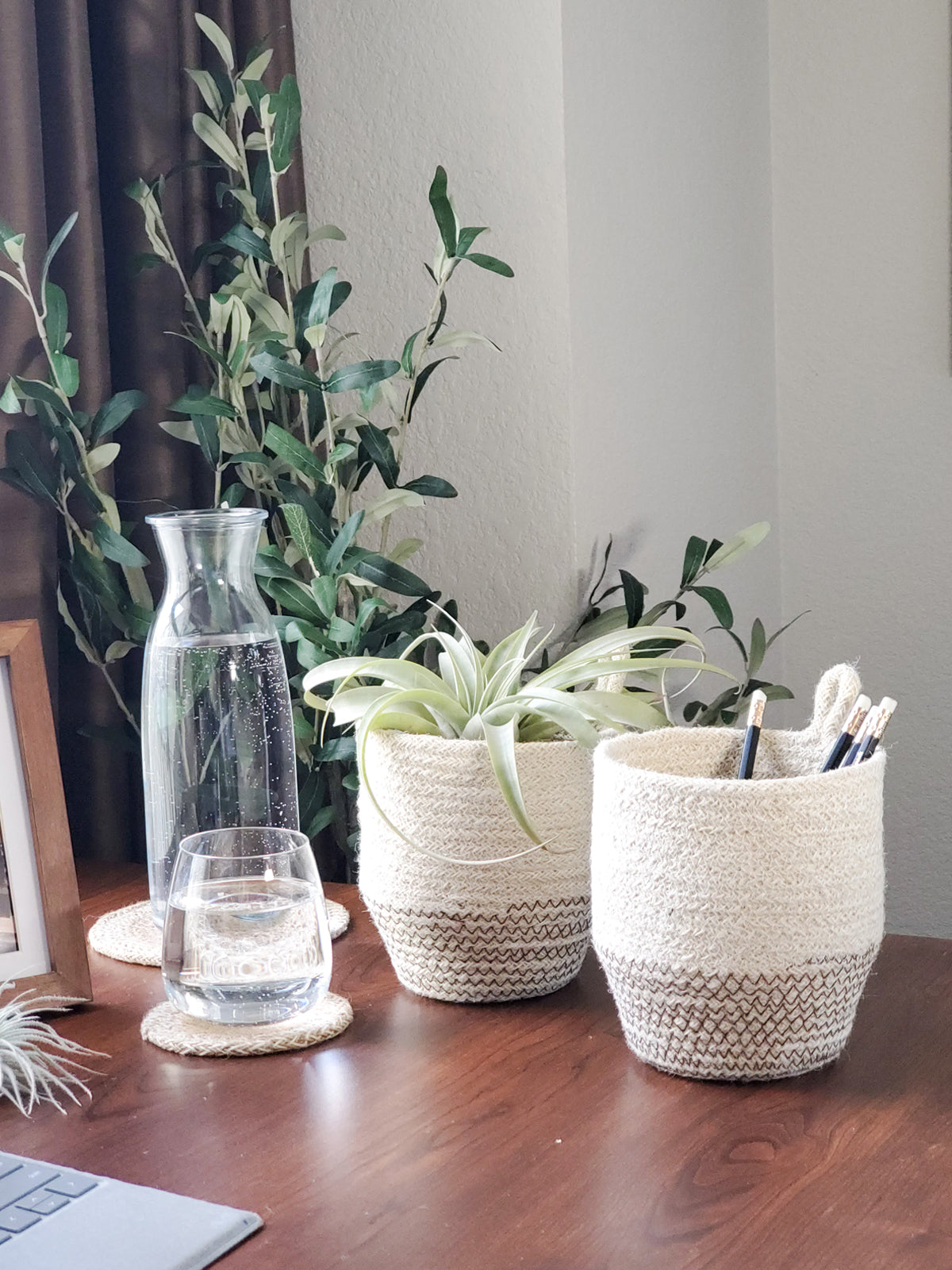 The Amari Loop Bin - Black, a beige and black woven basket featuring a loop handle, is elegantly displayed on a plain white background. Sustainably handmade by Fair Trade artisans, it seamlessly blends style with ethical craftsmanship.