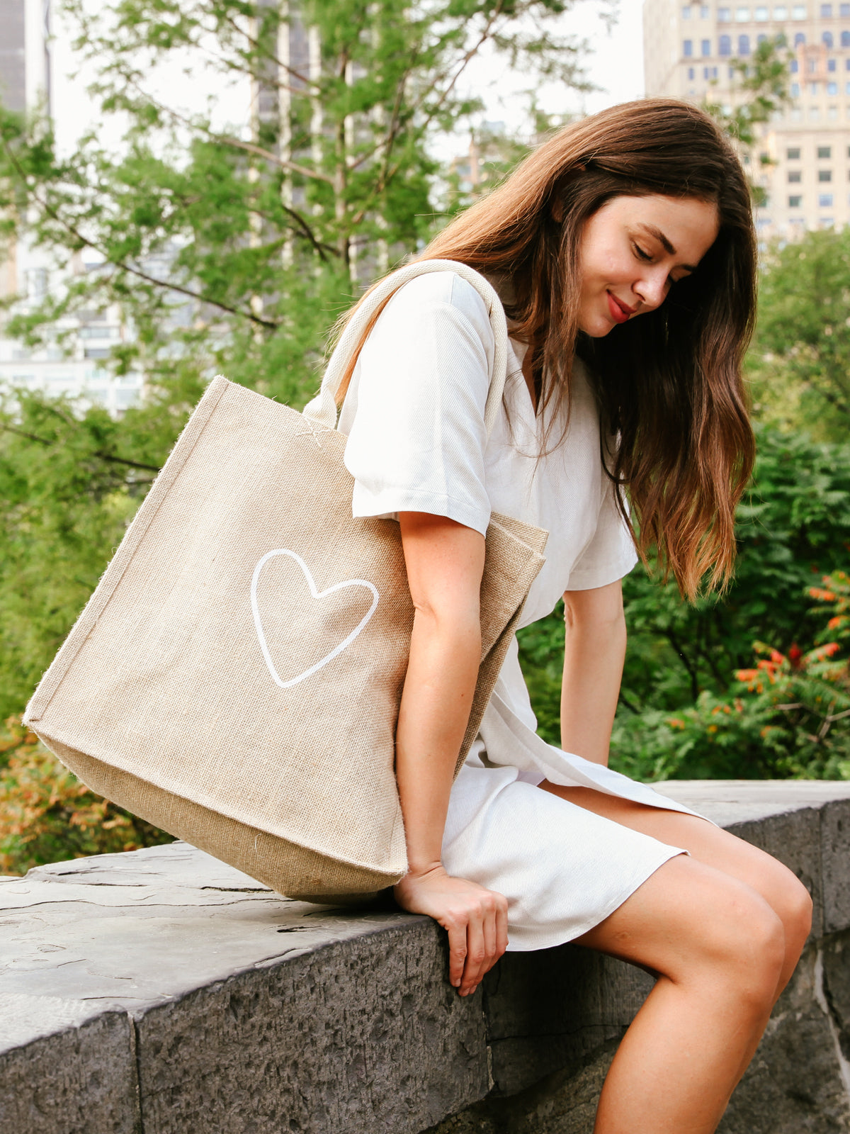 The Jute Canvas Market Bag - Love, featuring a delightful heart design and beige handles, crafted by Fair Trade artisans, is displayed gracefully against a plain background.