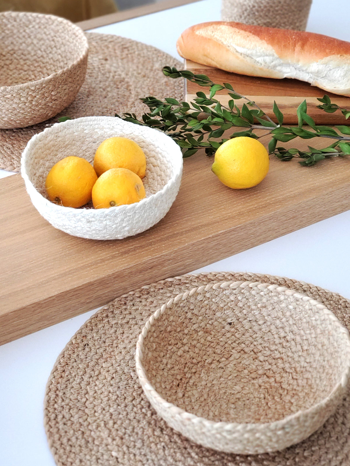 On a flat surface against a plain background, a set of four Kata Candy Bowls in white, crafted by fair trade artisans, is displayed. These versatile woven straw baskets highlight the beauty and authenticity of natural jute.