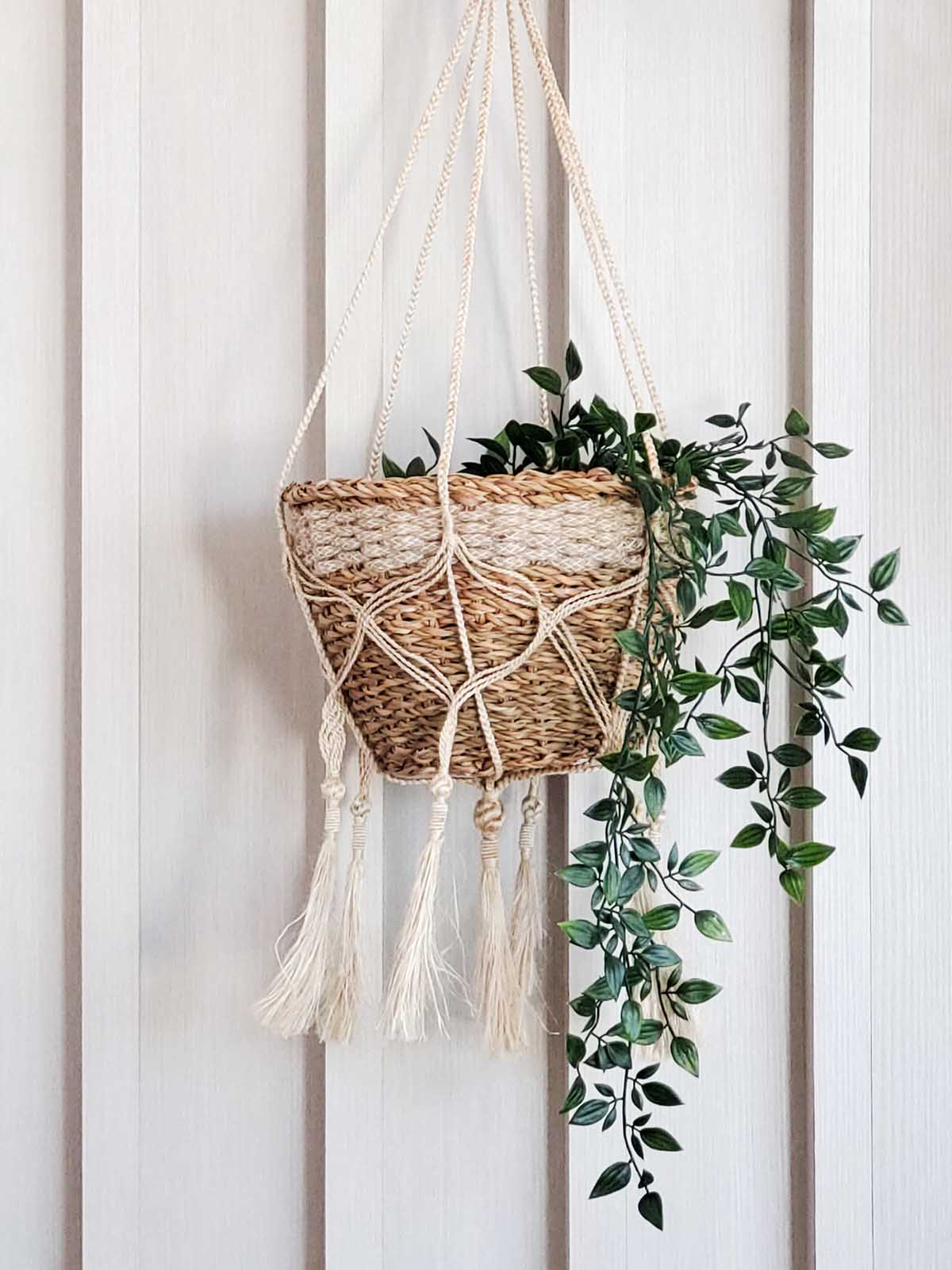 The Plant Hanger - Bitan is a handmade jute hanger crafted by Fair Trade artisans, featuring natural fibers with a striking black base and playful tassels.