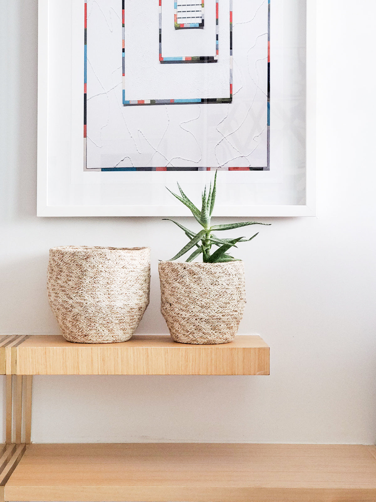 The Agora Bin set includes two woven baskets of different sizes, meticulously handmade from natural fibers. These exquisite pieces are adorned with jute yarn detailing and embody fair trade principles.