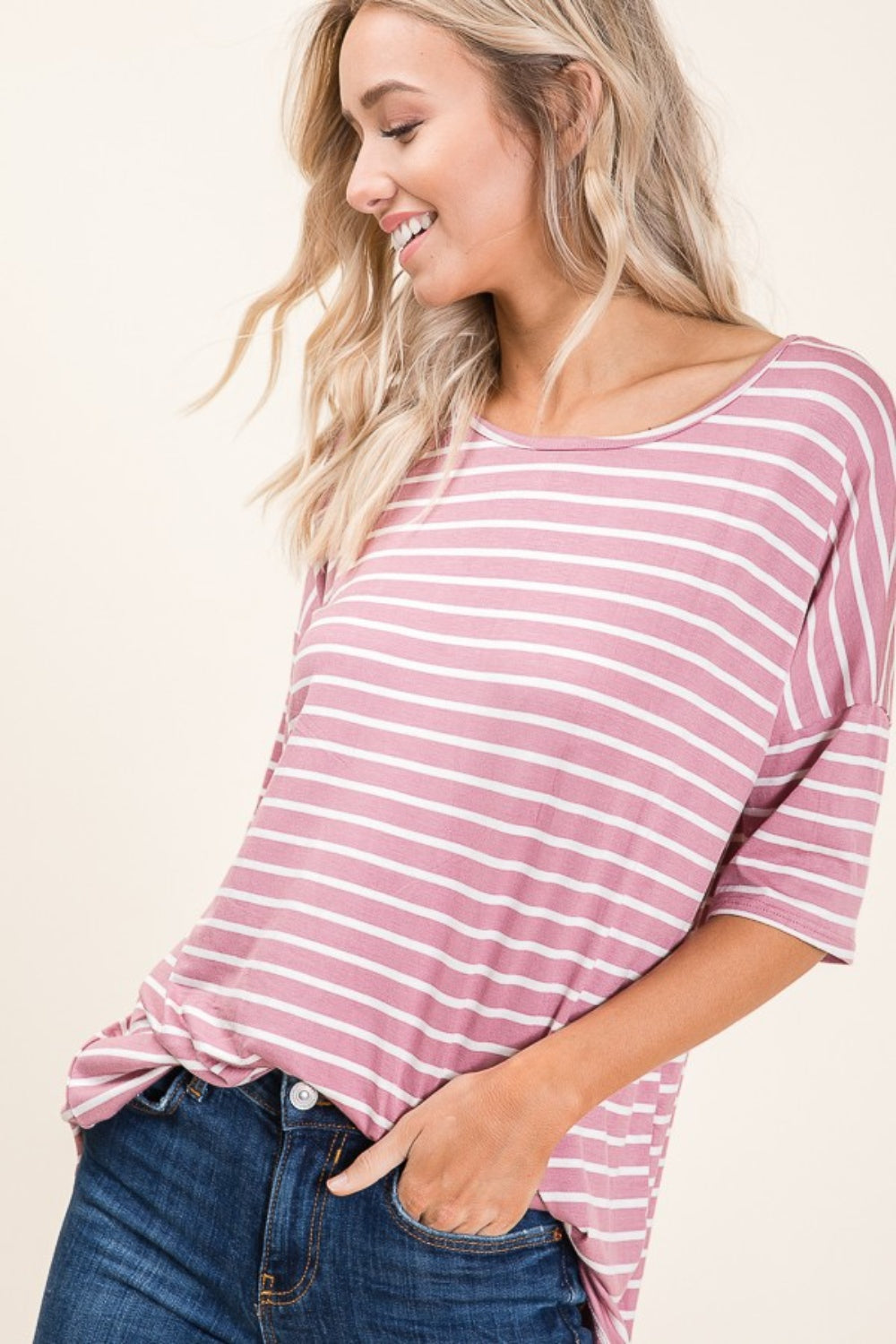 A person wearing a BOMBOM Striped Round Neck Half Sleeve T-Shirt in pink and white paired with blue jeans stands against a neutral background.