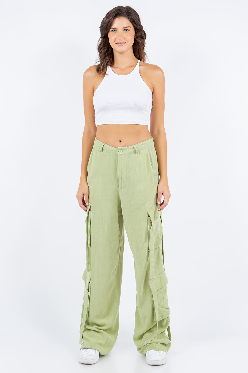 A person is wearing American Bazi light green linen wide leg cargo pants with multiple pockets and white sneakers.