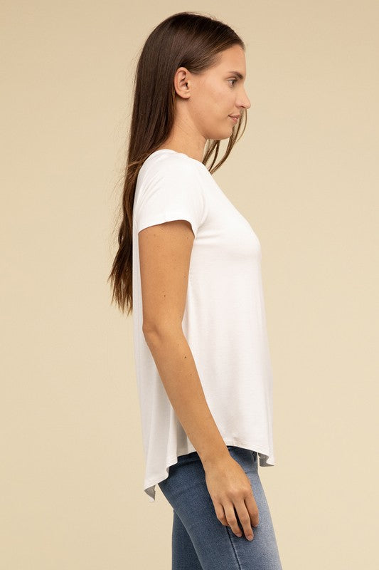 A person with long hair is wearing a blue Flowy Round Hem Rayon Short Sleeve Top and black pants, standing against a plain beige background.