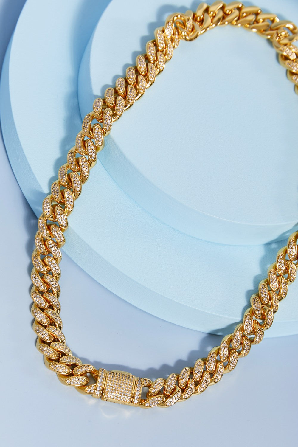 Brass Curb Chain Necklace elegantly displayed on a light blue round surface.