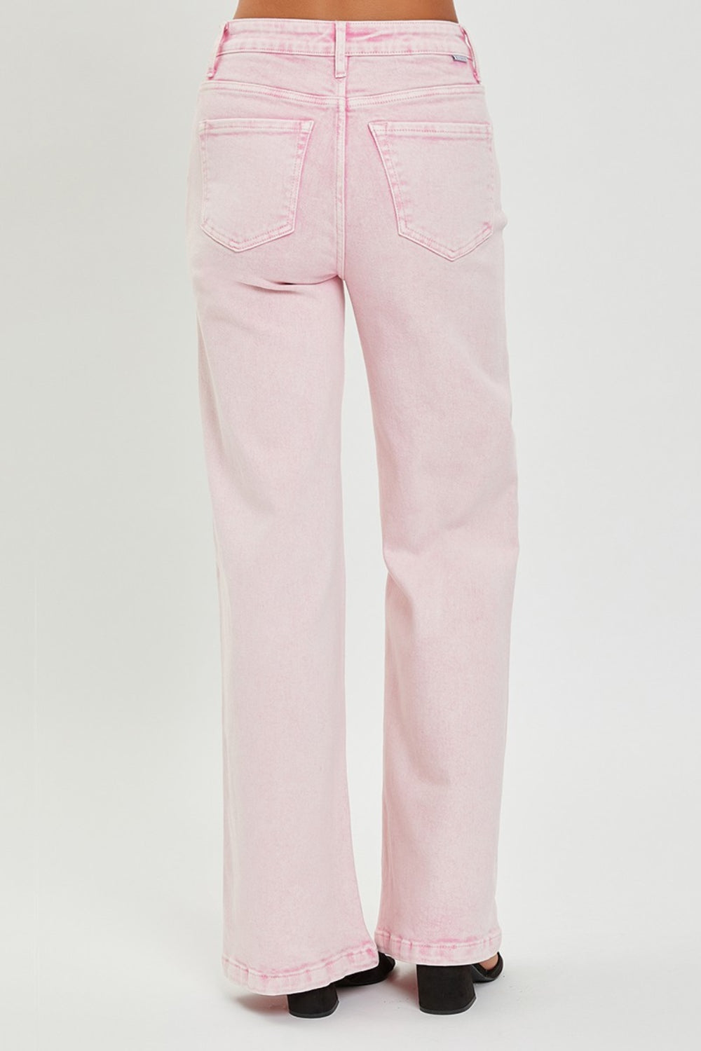 Someone is wearing RISEN Full Size High Rise Tummy Control Wide Leg Jeans in light pink, paired with black heeled sandals against a plain white background.