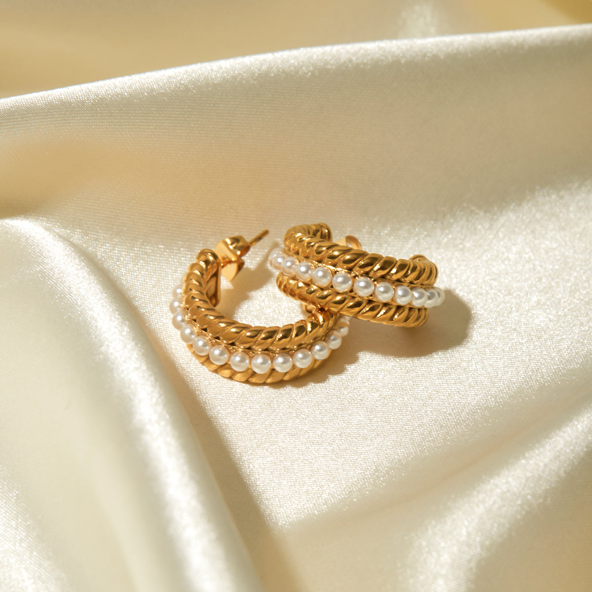 Close-up of a person's ear wearing Stainless Steel Pearl C-Hoop Earrings featuring a row of small synthetic pearls.