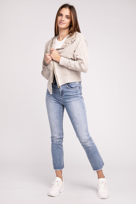 Woman in a Acid Wash Cotton Waffle Hooded Zip-Up Jacket with pockets and black pants, smiling and posing with hands on hips, against a light gray background.