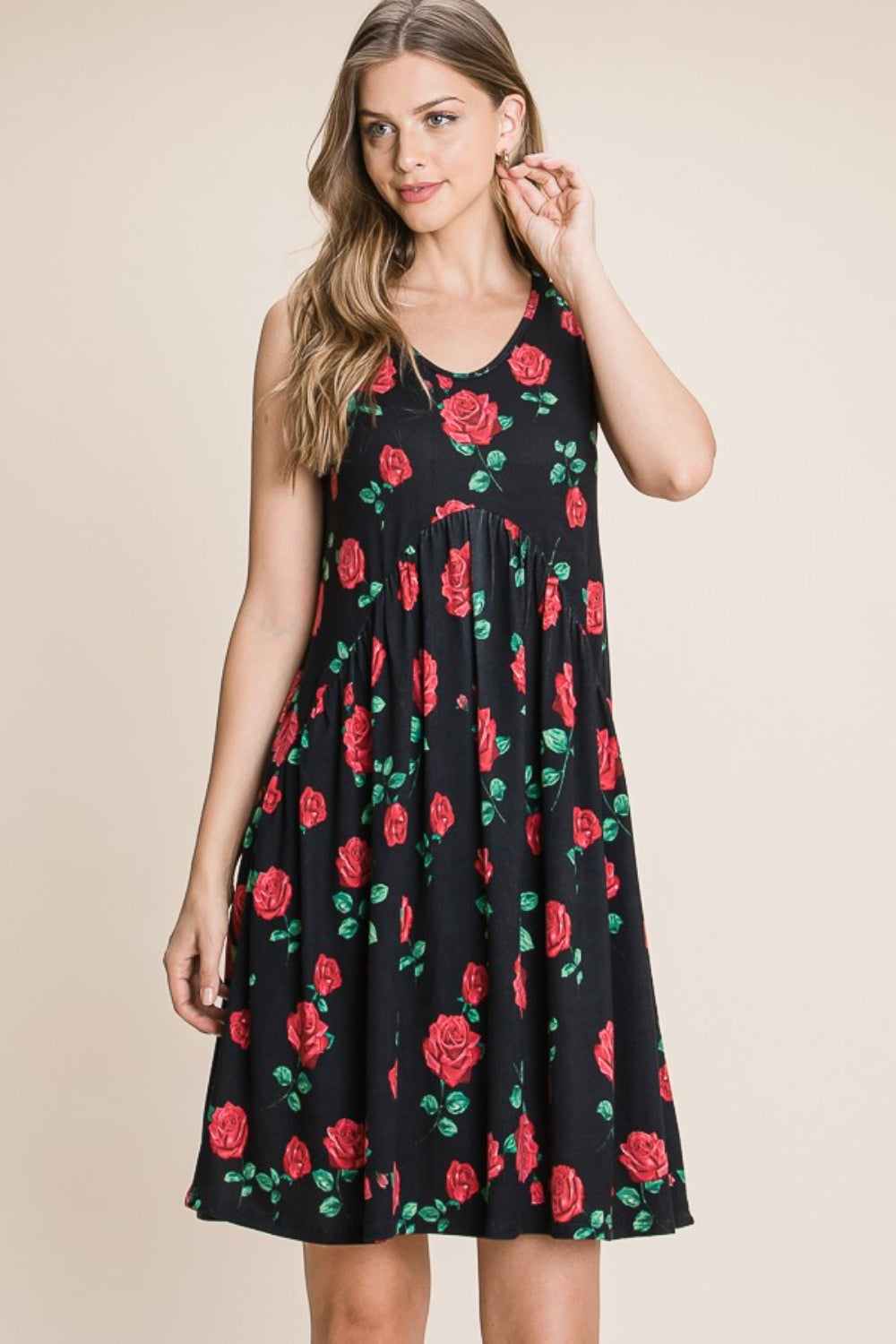 A woman is wearing a sleeveless BOMBOM Floral Ruched Tank Dress adorned with a black and red rose pattern. She is smiling and standing against a neutral background.