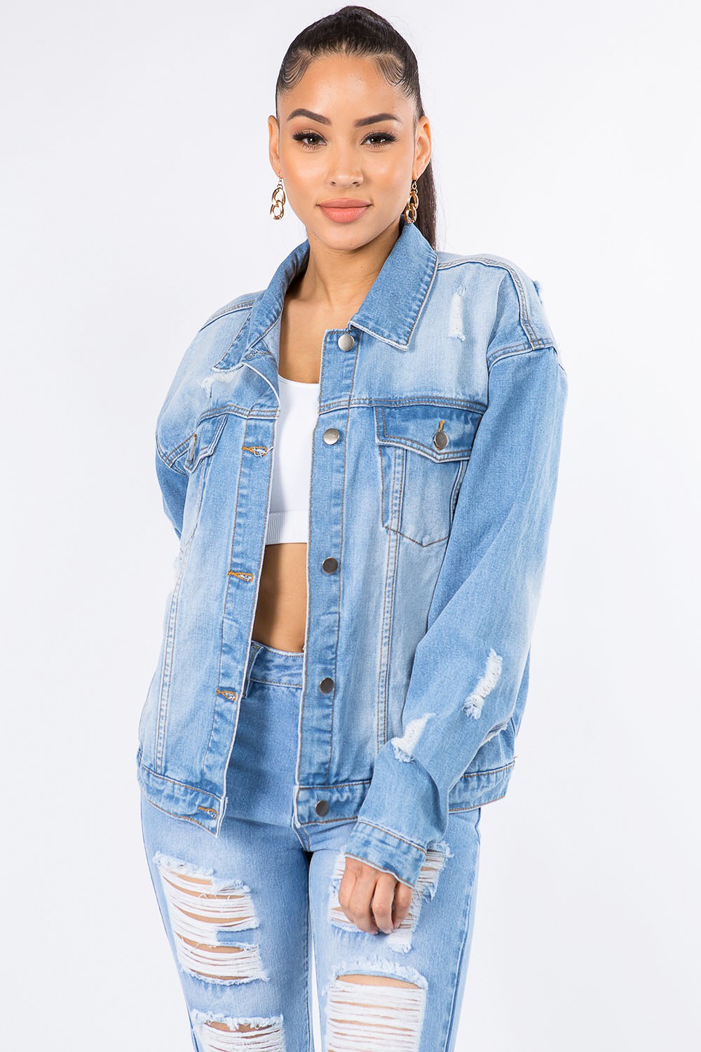 A person wearing the American Bazi Graphic Distressed Long Sleeve Denim Jacket and matching ripped jeans over a white top, standing against a plain white background.