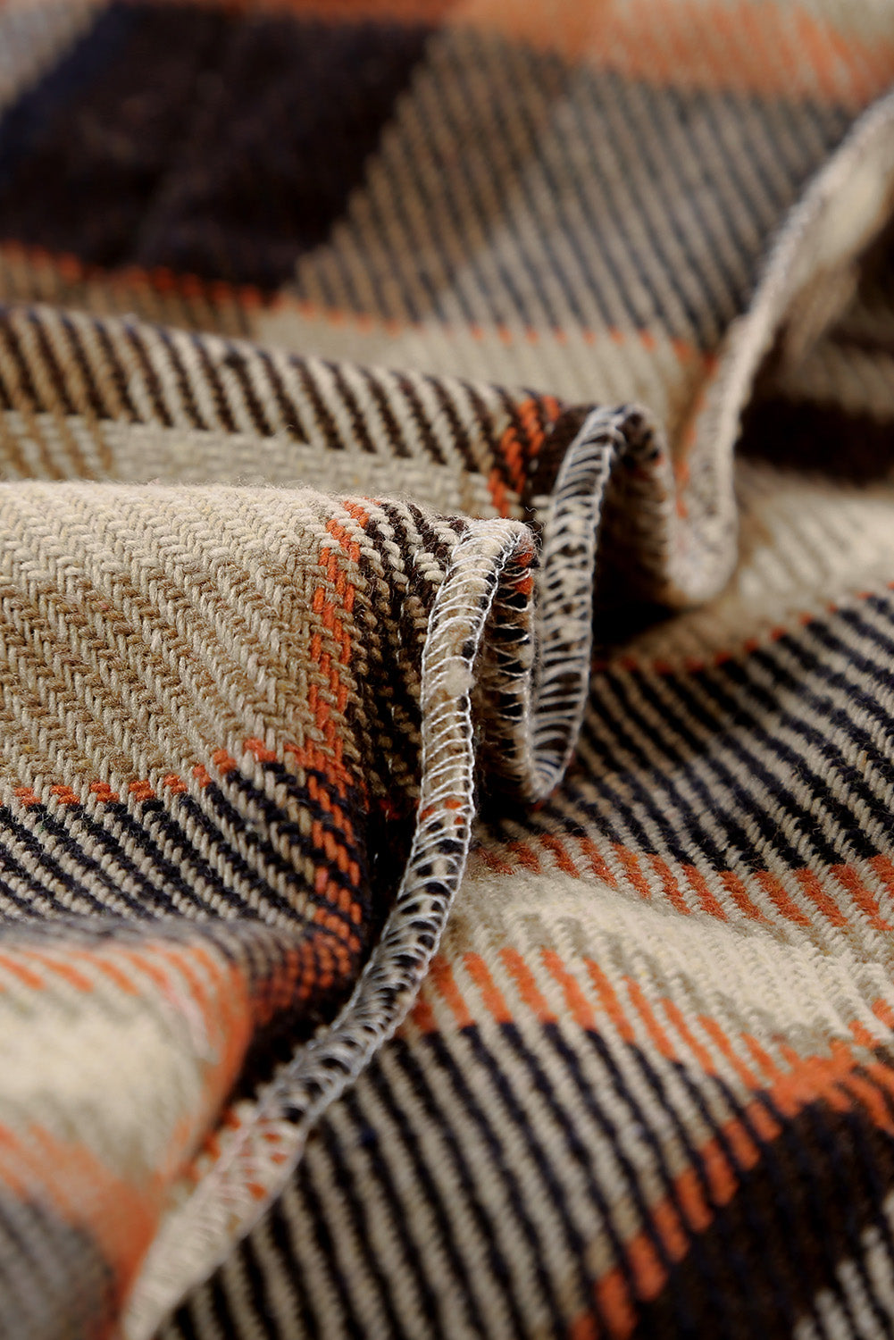 A person wearing a Brown Plaid Button Up Long Sleeve Flannel Shacket layered over a white top with ripped jeans and holding a brown handbag stands against a textured gray wall.