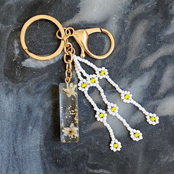 Baby Daisy Initial Key Chain alphabet keychains with real daisy flowers and gold flakes on a marble surface.