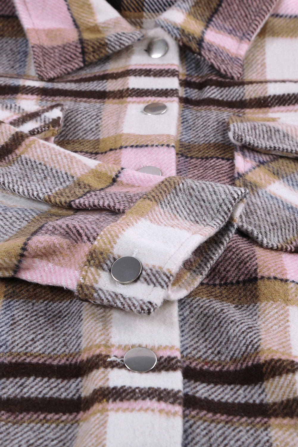 A person wearing a Brown Plaid Button Up Long Sleeve Flannel Shacket layered over a white top with ripped jeans and holding a brown handbag stands against a textured gray wall.