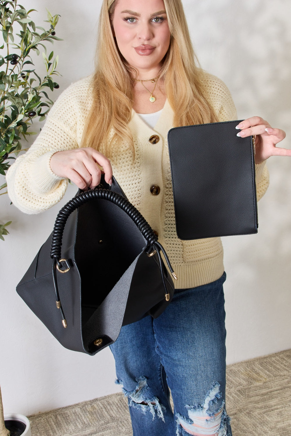 A person in a cream sweater holds a medium-size SHOMICO Zipper Detail Shoulder Bag with gold metal zipper pockets.