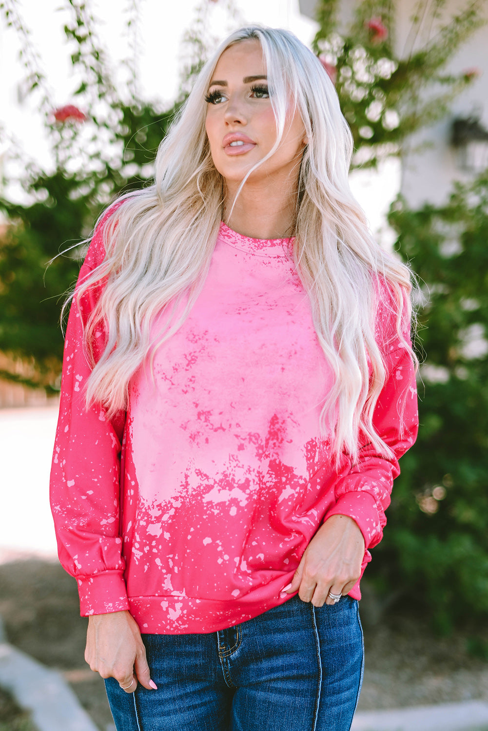 Person with long blonde hair wearing a Rose Tie Dye Long Sleeve Pullover Sweatshirt and blue jeans, standing outdoors with back to the camera.